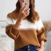Women in light brown and white sweater holding cell phone