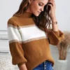 Women in light brown and white sweater with hand in her hair