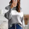 Women in Grey and white sweater holding a cell phone taking a picture
