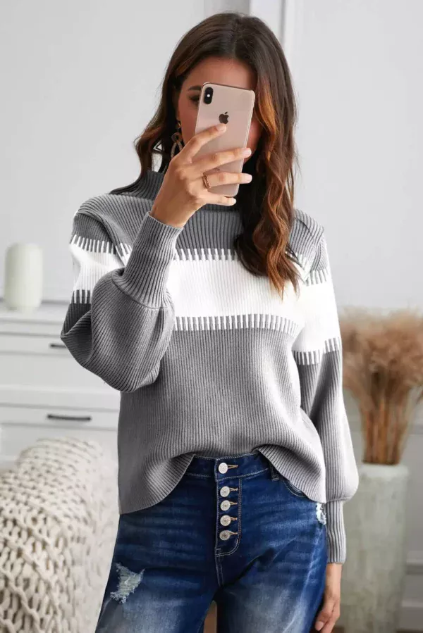 Women in Grey and white sweater holding a cell phone taking a picture